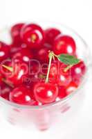 cherry with green leaf and a cup of cherries on a white backgrou