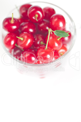 cherry with green leaf and a cup of cherries on a white backgrou