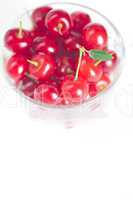 cherry with green leaf and a cup of cherries on a white backgrou