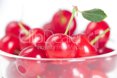 cherry with green leaf and a cup of cherries on a white backgrou