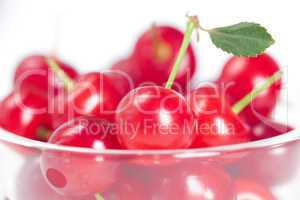 cherry with green leaf and a cup of cherries on a white backgrou