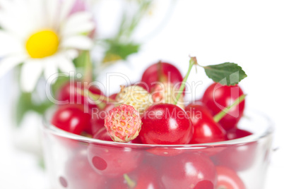 glass cup with cherries and wild strawberries and a bouquet of w