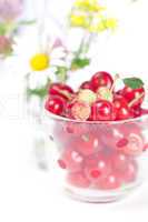 glass cup with cherries and wild strawberries and a bouquet of w