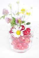 glass cup with cherries and a bouquet of wildflowers