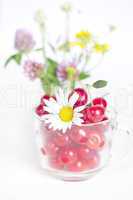 glass cup with cherries and a bouquet of wildflowers