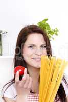 lächelnde junge frau hält tomate und spaghetti