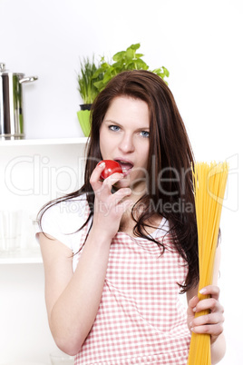 junge frau hält spaghetti und möchte tomate essen