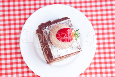 beautiful cake with strawberry on plaid fabric