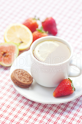 cup of tea,cookie, fig and strawberries on a plate