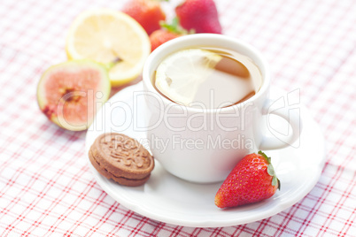 cup of tea,cookie, fig and strawberries on a plate