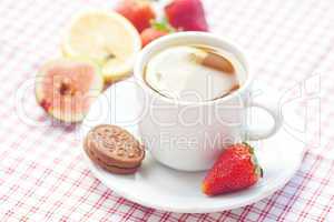 cup of tea,cookie, fig and strawberries on a plate