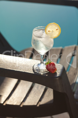 Swimming pool, lounge, a wine glass with ice, lemon and strawber