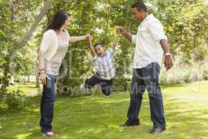 Hispanic Mother and Father Swinging Son in the Park