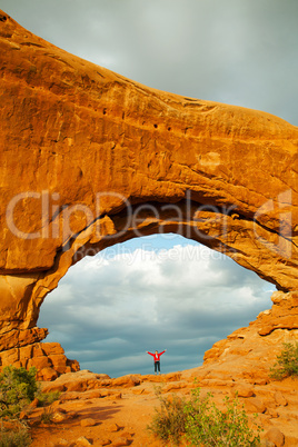 woman staying with raised hands inside an arch