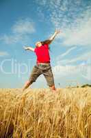 teen girl jumping at a wheat field