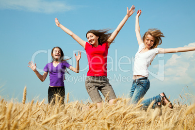 teen girls jumping at a wheat field