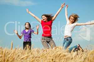 teen girls jumping at a wheat field