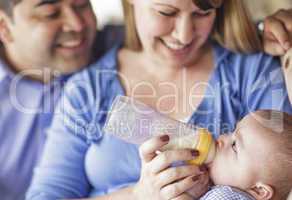 Happy Mixed Race Couple Bottle Feeding Their Son