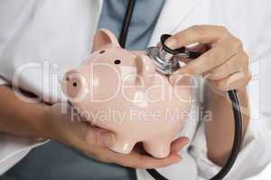 Doctor Holding Stethoscope to Piggy Bank