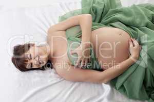 Happy pregnant woman lying in bed