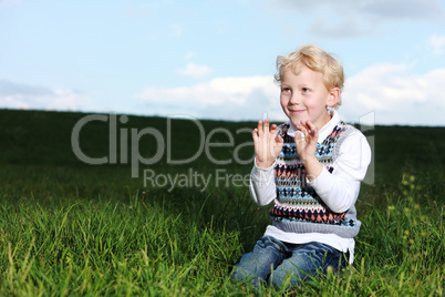 Impish little boy kneeling in green field