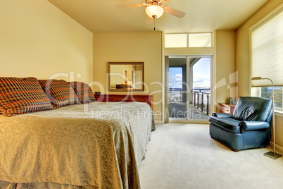 Bedroom with large bed, blue chair and bbalcony door.