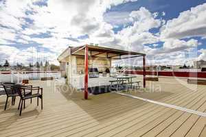 Apartment building roof top grill area with chairs.