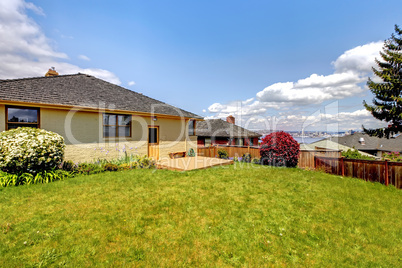 Summer backyard with fence and one story home.