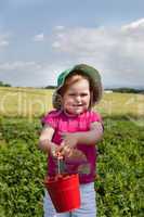 Kleinkind hält Eimer mit Erdbeeren