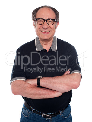 Cheerful old man standing with arms crossed