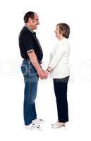 Aged couple looking at each other, holding hands