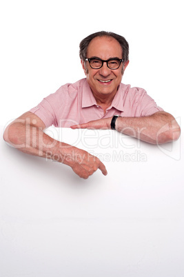 Happy old man pointing at blank billboard