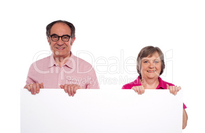 Aged couple displaying blank billboard