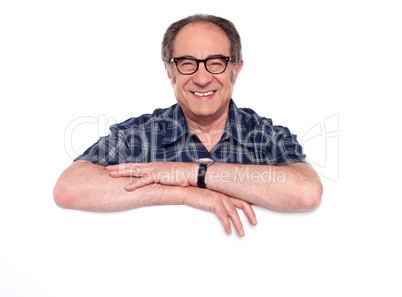 Smiling aged man posing with blank billboard