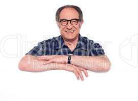 Smiling aged man posing with blank billboard