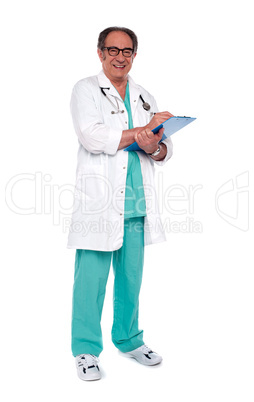 Aged doctor holding clipboard. Full length shot