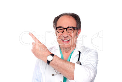 Mature doctor pointing upwards and away