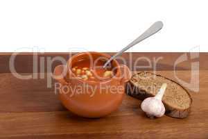 Soup in ceramic pot with bread and garlic