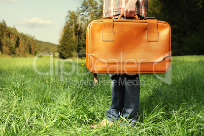 Man with travel bag standing on green lawn