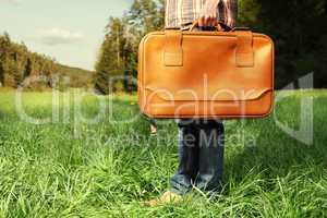 Man with travel bag standing on green lawn