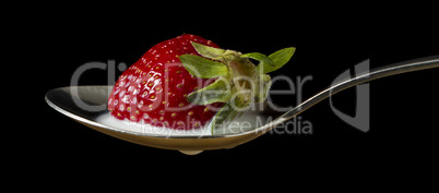 red, ripe strawberry falling in spoon with milk