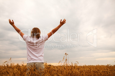 young man staying with raised hands at sunset time