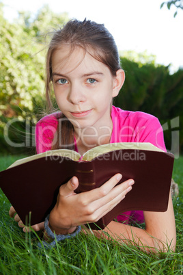 Teen girl reading the Bible outdoors