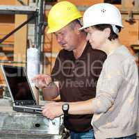 Civil engineer and construction worker looking at the laptop