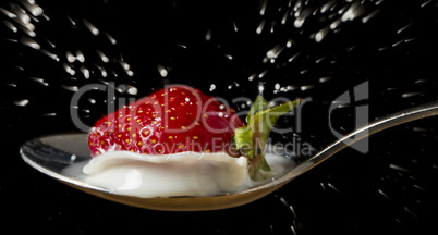 red, ripe strawberry falling in spoon with milk