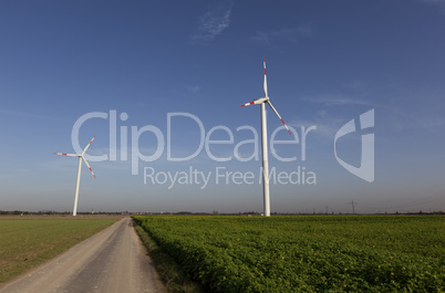 Wind Turbines with blue sky and the sun shining on green