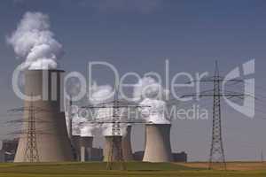 Brown coal power plant with huge cooling towers and steam and powerlines