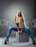 Beautiful girl in jeans posing on cube