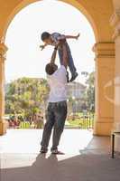 African American Father Lifting Mixed Race Son in the Park