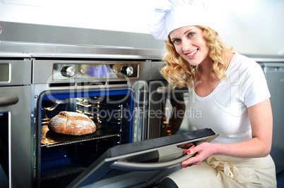Pretty baker opening an oven door